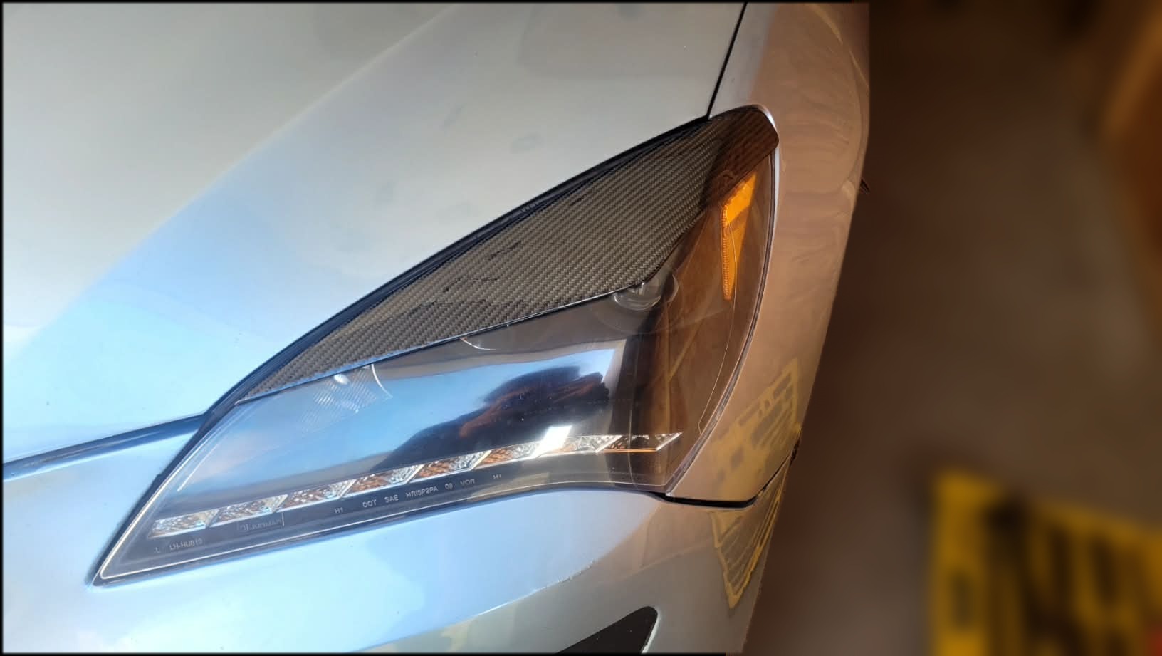 Gros plan du phare de la Genesis Coupe avec eyelid en fibre de carbone